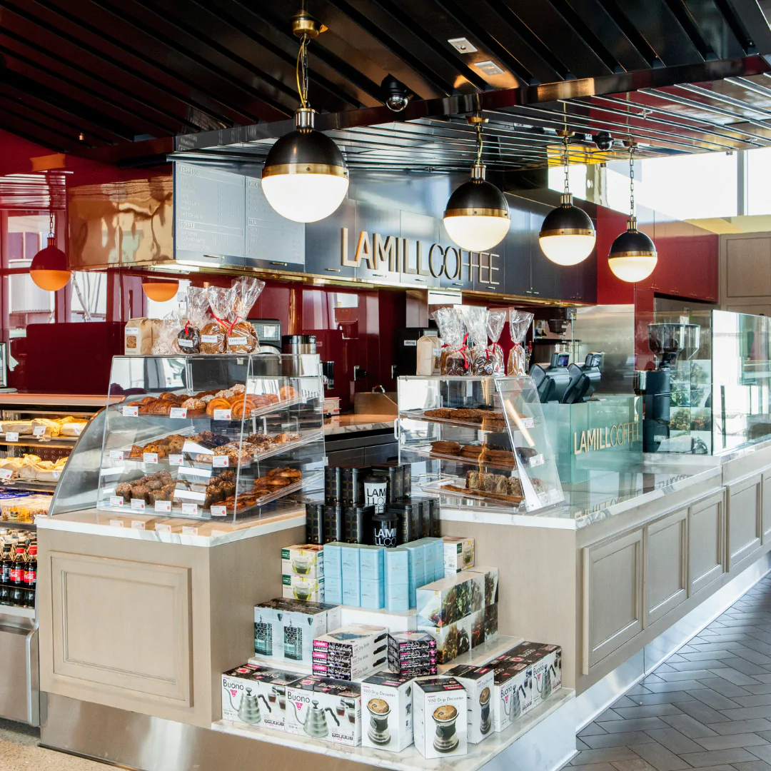Coffee shop counter with pastry display and hanging lights.