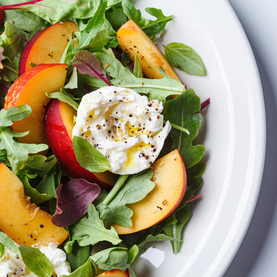 Fresh salad with peach slices and burrata cheese.