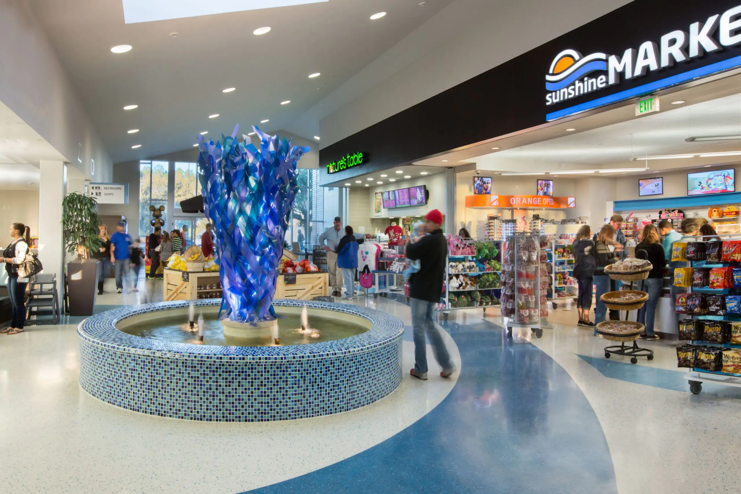 Airport marketplace with fountain and retail shops.