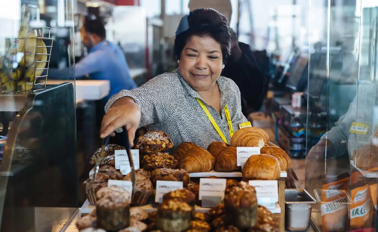 Employee placing pastries on the counter.
