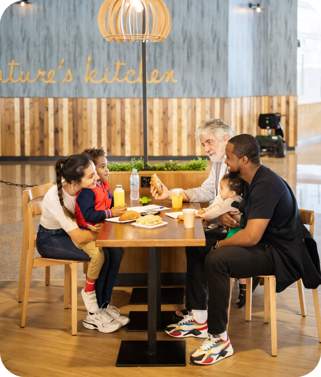 Family enjoying a meal together at a restaurant table in a food court.