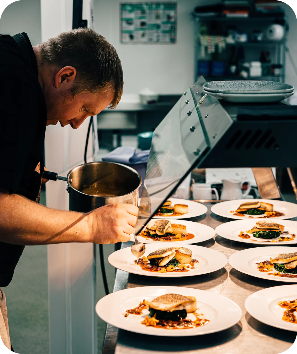 Chef plating gourmet dishes in a professional restaurant kitchen.